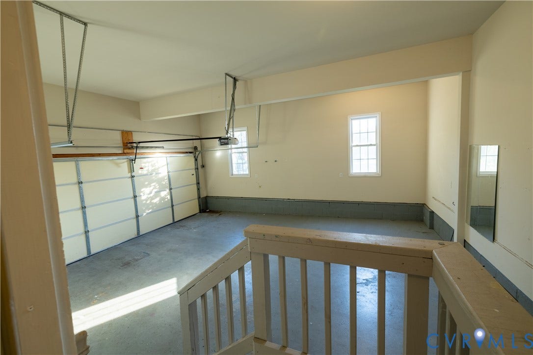 Multi-vehicle garage featuring neutral-toned walls, coated concrete flooring, dual windows, and an overhead door mechanism
