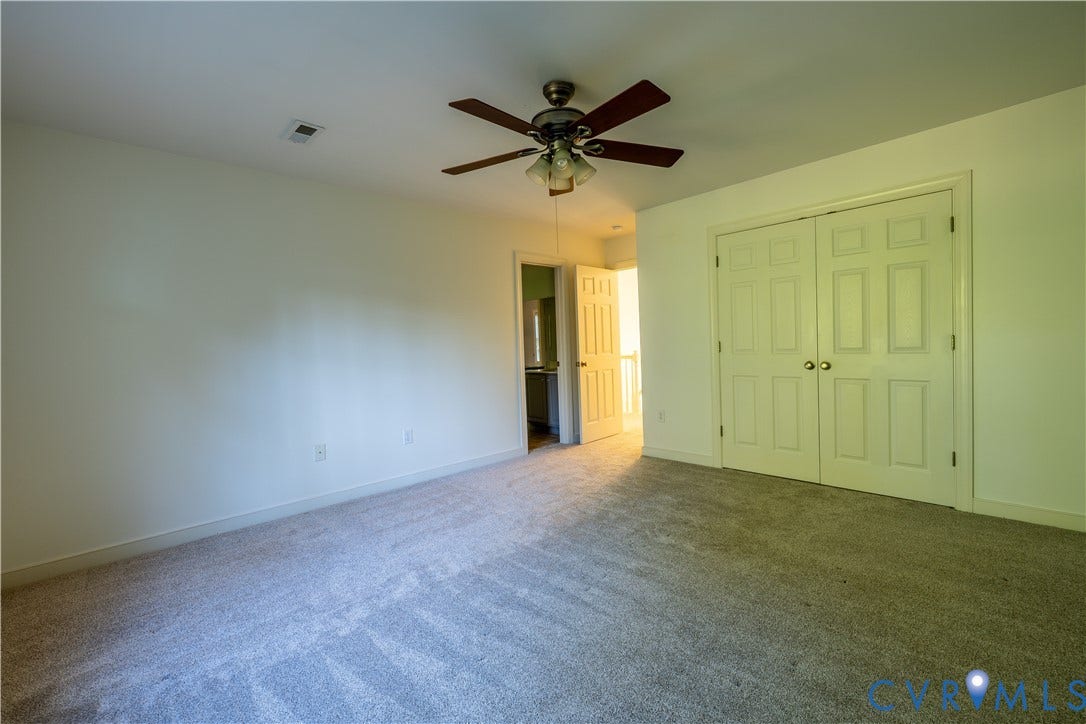 Neutral-toned wall-to-wall carpeting, dual-door reach-in closet, multi-blade ceiling fan with integrated lighting, and white six-panel interior doors