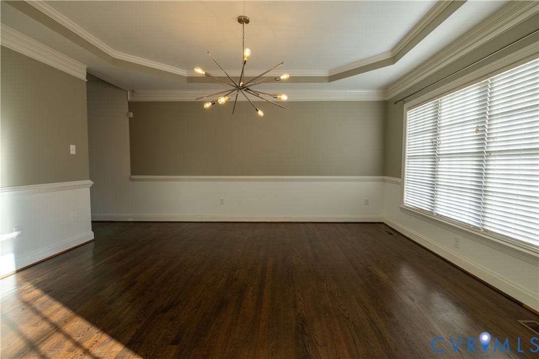 Tray ceiling with crown molding, wood-finish flooring, mid-century modern style sputnik chandelier, horizontal slat blinds, and wainscoting