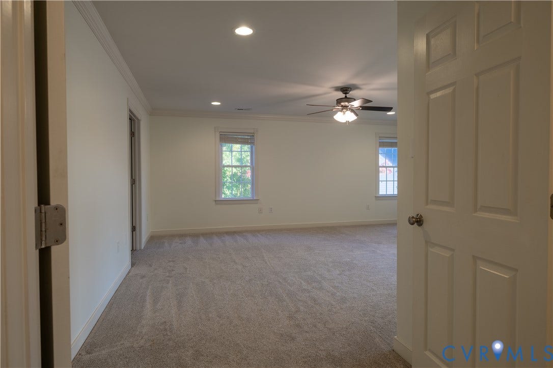 Spacious interior featuring neutral carpeting, crown molding, recessed lighting, and a multi-light ceiling fan