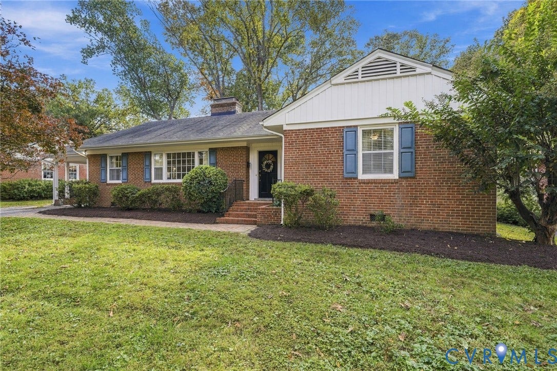 7506 N Pinehill Drive, Henrico, VA 23228 Traditional brick exterior featuring white vertical siding accents, dark-toned shutters, a multi-pane grid window, and a brick front entry staircase
