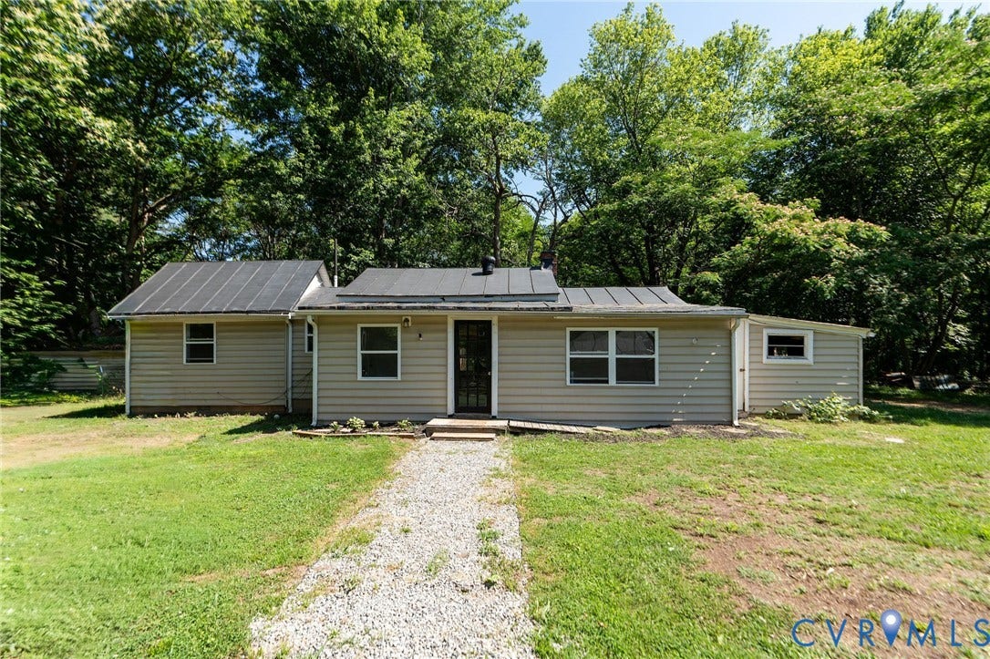 14043 Jefferson Highway, Louisa, VA 23024 Single-story residence featuring light-toned horizontal siding, a dark metal roof, and a gravel walkway leading to a central entrance