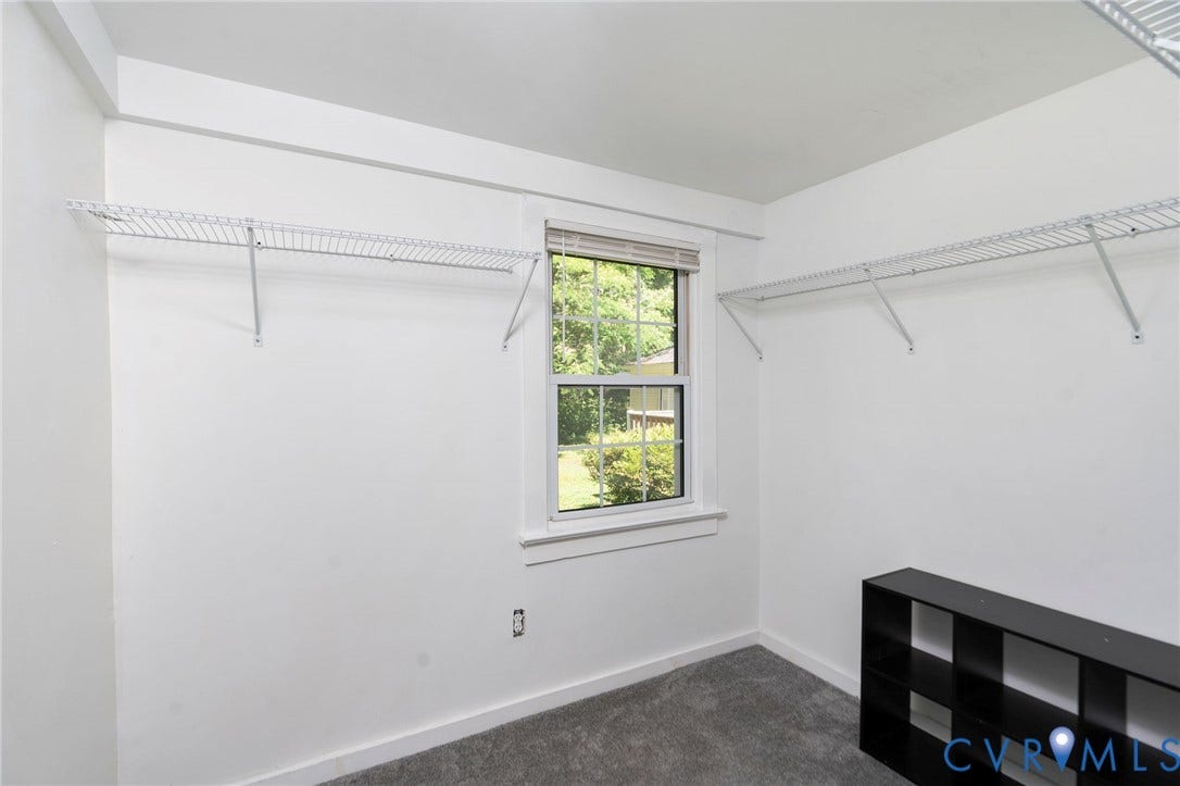 14043 Jefferson Highway, Louisa, VA 23024 Storage space featuring dual wall-mounted white wire shelving units, a double-hung window with a wood-trimmed frame, and neutral carpeting