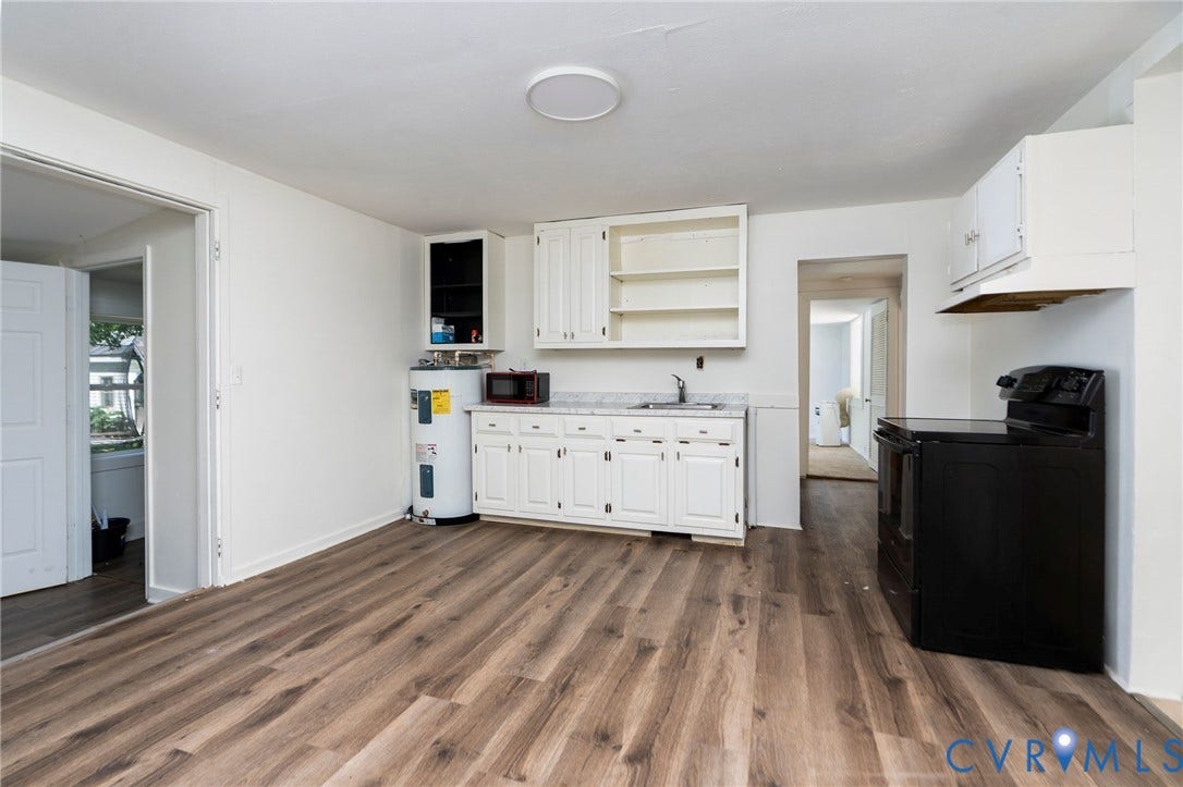 14043 Jefferson Highway, Louisa, VA 23024 Kitchen featuring wood-finish flooring, white cabinetry, light-toned countertop, and black range