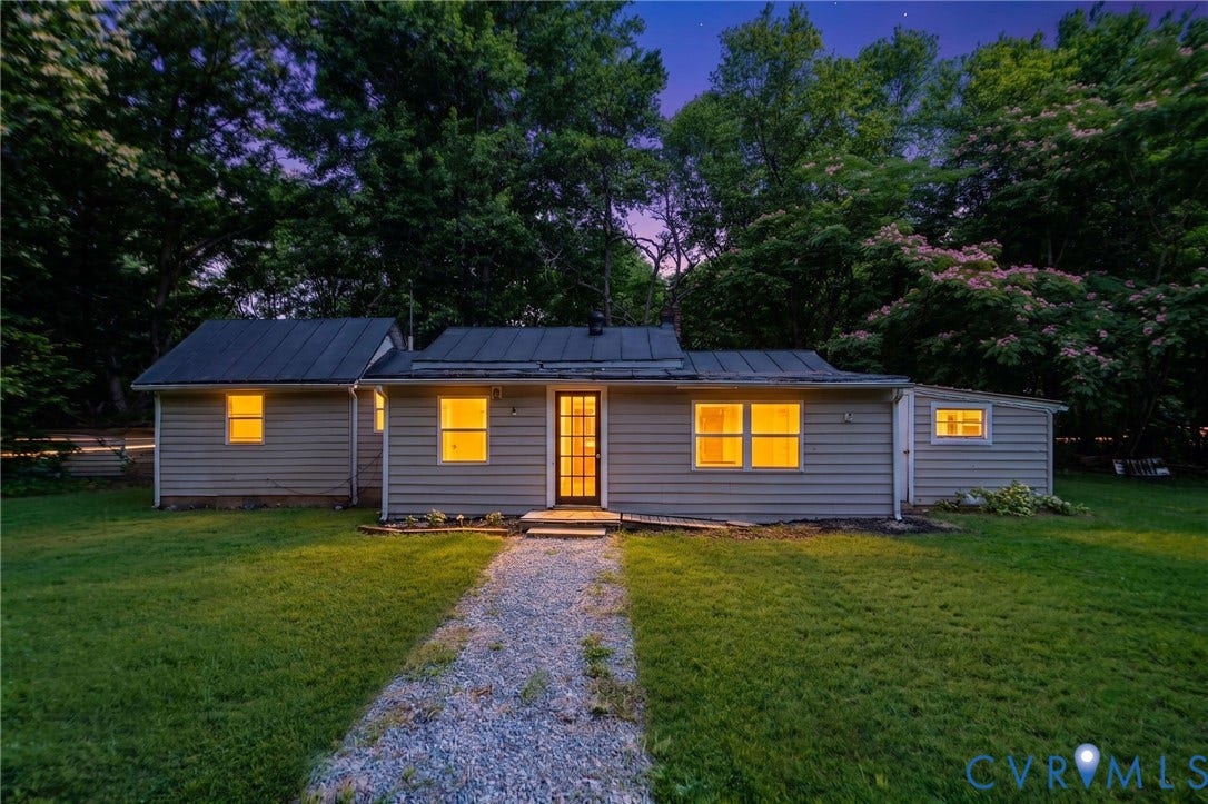 14043 Jefferson Highway, Louisa, VA 23024 Single-story exterior featuring light-toned horizontal siding, a dark metal roof, a multi-pane glass entry door, and a gravel pathway leading to the entrance