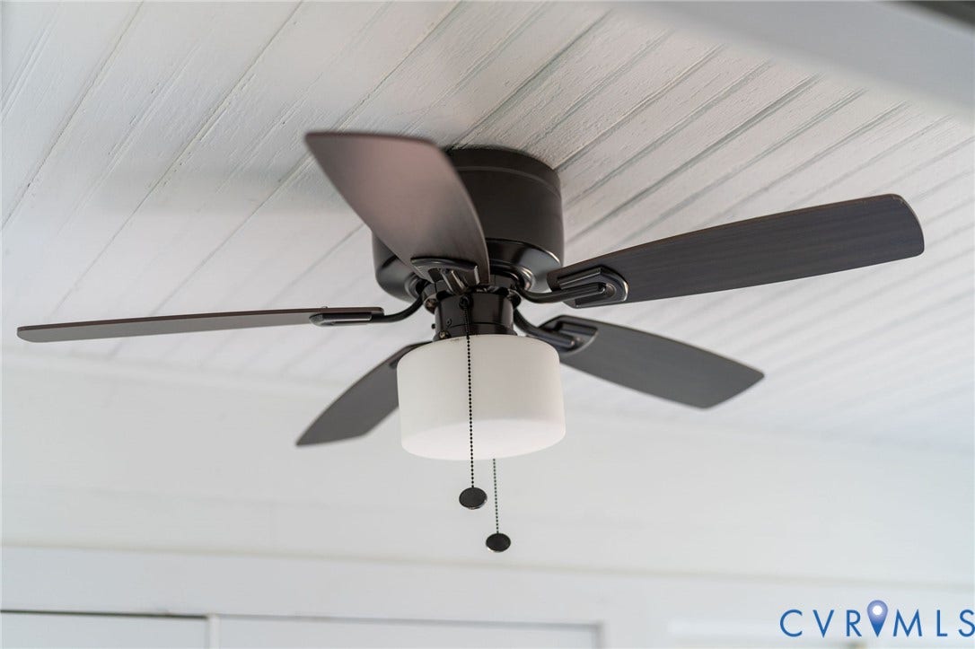 14043 Jefferson Highway, Louisa, VA 23024 Matte black five-blade ceiling fan with integrated cylindrical frosted glass light fixture and bead-chain pull switches, mounted to a white beaded-plank ceiling