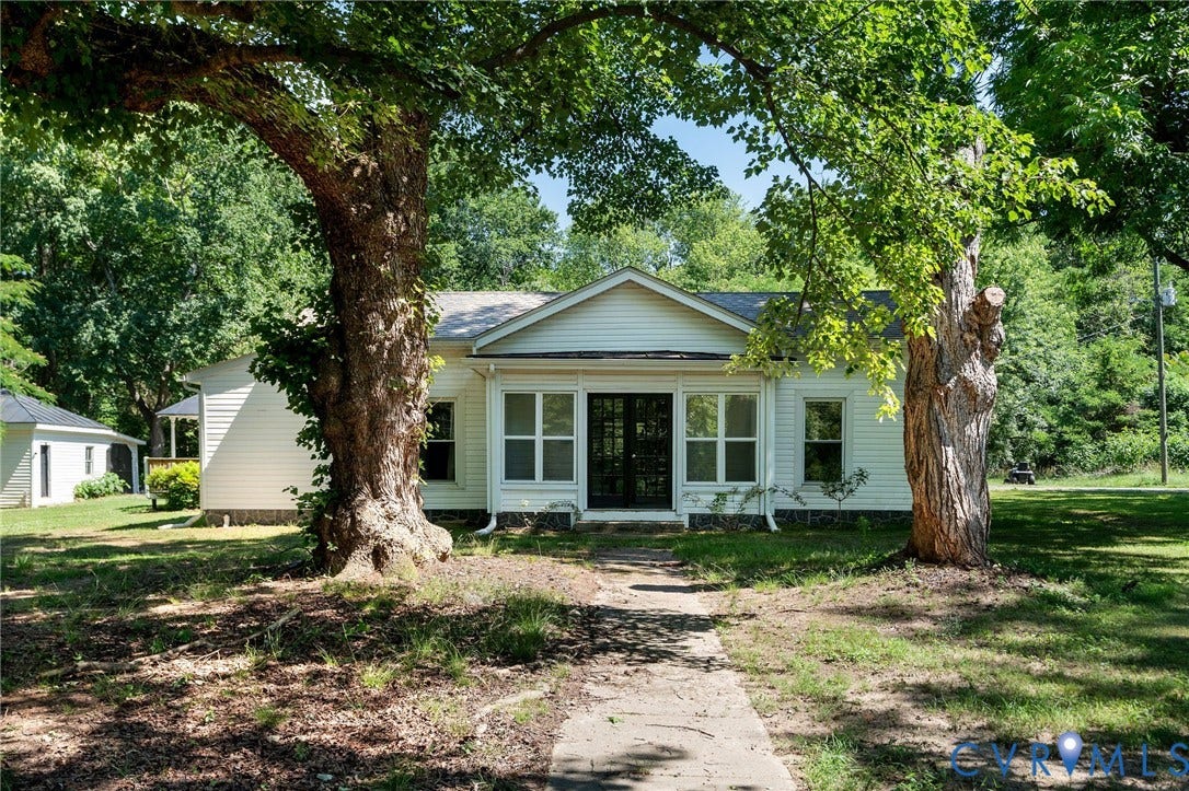 14043 Jefferson Highway, Louisa, VA 23024 Single-story exterior featuring white horizontal siding, a central gable roofline, multi-pane glass entry doors, and mature trees
