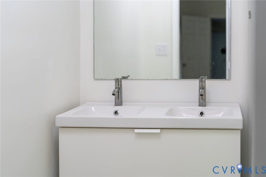 14043 Jefferson Highway, Louisa, VA 23024 Double-sink vanity featuring a white cabinet base, integrated dual-basin countertop, chrome faucets, and a wall-mounted mirror