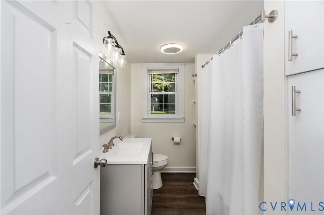 14043 Jefferson Highway, Louisa, VA 23024 Bathroom featuring a vanity with a white countertop and basin, wood-finish flooring, built-in cabinetry, and multi-light vanity fixture