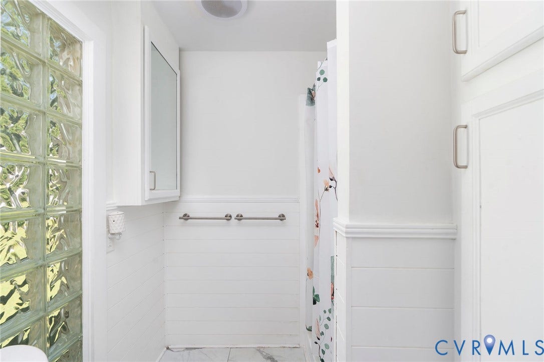 14043 Jefferson Highway, Louisa, VA 23024 Bathroom featuring glass block accent wall, white horizontal wall paneling, built-in medicine cabinet, and metal hardware