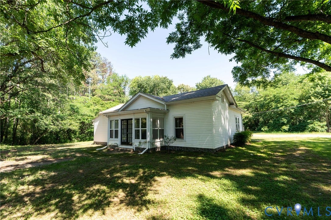 14043 Jefferson Highway, Louisa, VA 23024 Exterior featuring white horizontal siding, gable roofline, multi-pane glass entry doors, and a natural tree canopy setting