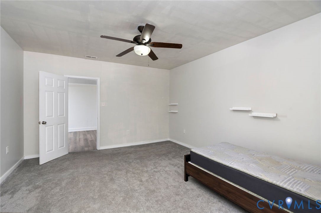 14043 Jefferson Highway, Louisa, VA 23024 Neutral interior room featuring wall-to-wall carpeting, a multi-blade ceiling fan with integrated lighting, and white floating wall shelves