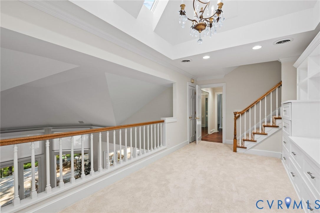 11429 Barrington Bridge Court, Henrico, VA 23233 Vaulted ceiling with skylight, custom built-in cabinetry, decorative chandelier, and wood-railed staircase
