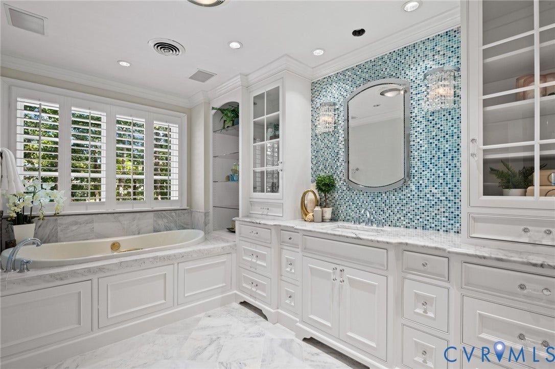 11429 Barrington Bridge Court, Henrico, VA 23233 Custom cabinetry with glass-fronted displays, tiled mosaic accent wall, stone-surround soaking tub, stone tile flooring, and integrated recessed lighting