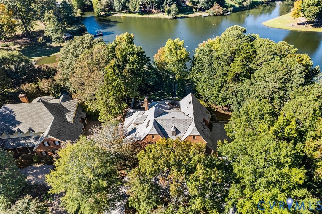 11429 Barrington Bridge Court, Henrico, VA 23233 Aerial perspective of a multi-gabled brick residence featuring a multi-layered roofline, stone chimney, and expansive wooded grounds situated along a lakefront