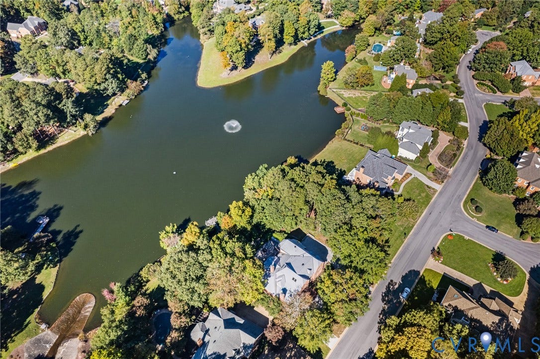 11429 Barrington Bridge Court, Henrico, VA 23233 Aerial perspective of residential properties bordering a lake with a central fountain, featuring mature trees, landscaped lawns, and paved thoroughfares