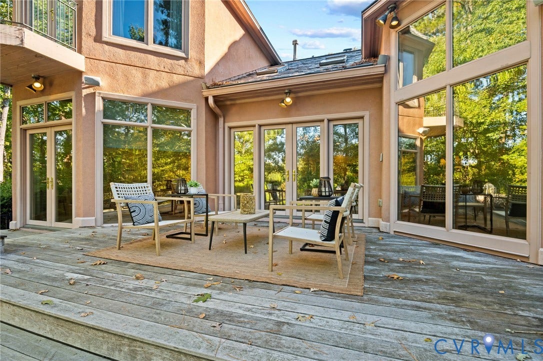 11429 Barrington Bridge Court, Henrico, VA 23233 Stucco exterior featuring extensive floor-to-ceiling glass paneling, multiple sets of glass-paneled double doors, and a wood-decked outdoor patio