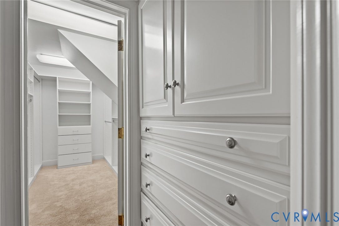 11429 Barrington Bridge Court, Henrico, VA 23233 Custom walk-in storage featuring white cabinetry with raised-panel doors, integrated drawer banks, adjustable shelving, and carpet flooring