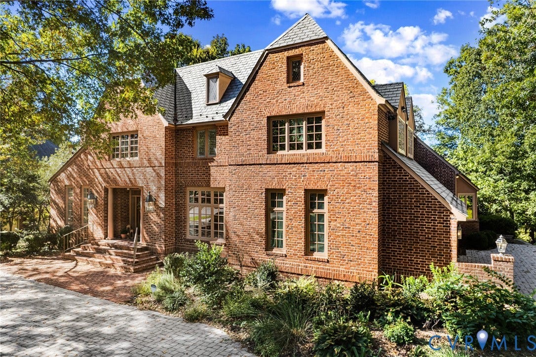 11429 Barrington Bridge Court, Henrico, VA 23233 Tudor-style brick exterior featuring a steep-pitched roofline, multi-pane casement windows, stone-paved motor court, and detailed masonry facade