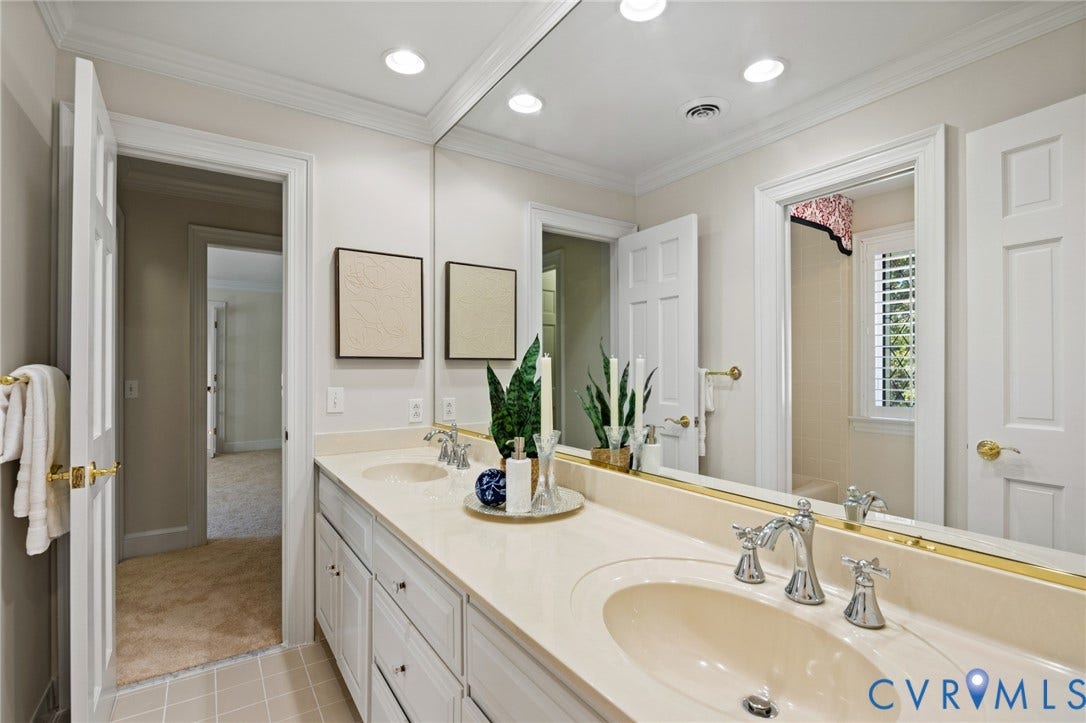 11429 Barrington Bridge Court, Henrico, VA 23233 Double-sink vanity featuring a solid-surface countertop, integrated oval basins, polished chrome fixtures, and white shaker-style cabinetry with crown molding