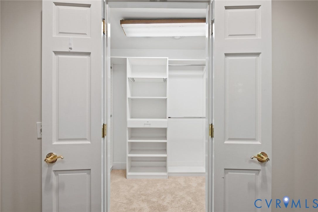 11429 Barrington Bridge Court, Henrico, VA 23233 Walk-in closet featuring white built-in shelving, a dedicated drawer unit, dual hanging rods, and neutral carpeting, enclosed by white paneled double doors with brass-finish hardware