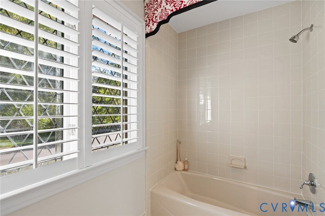 11429 Barrington Bridge Court, Henrico, VA 23233 Bathtub with square tile surround, polished chrome fixtures, and window featuring white plantation shutters and leaded glass accents