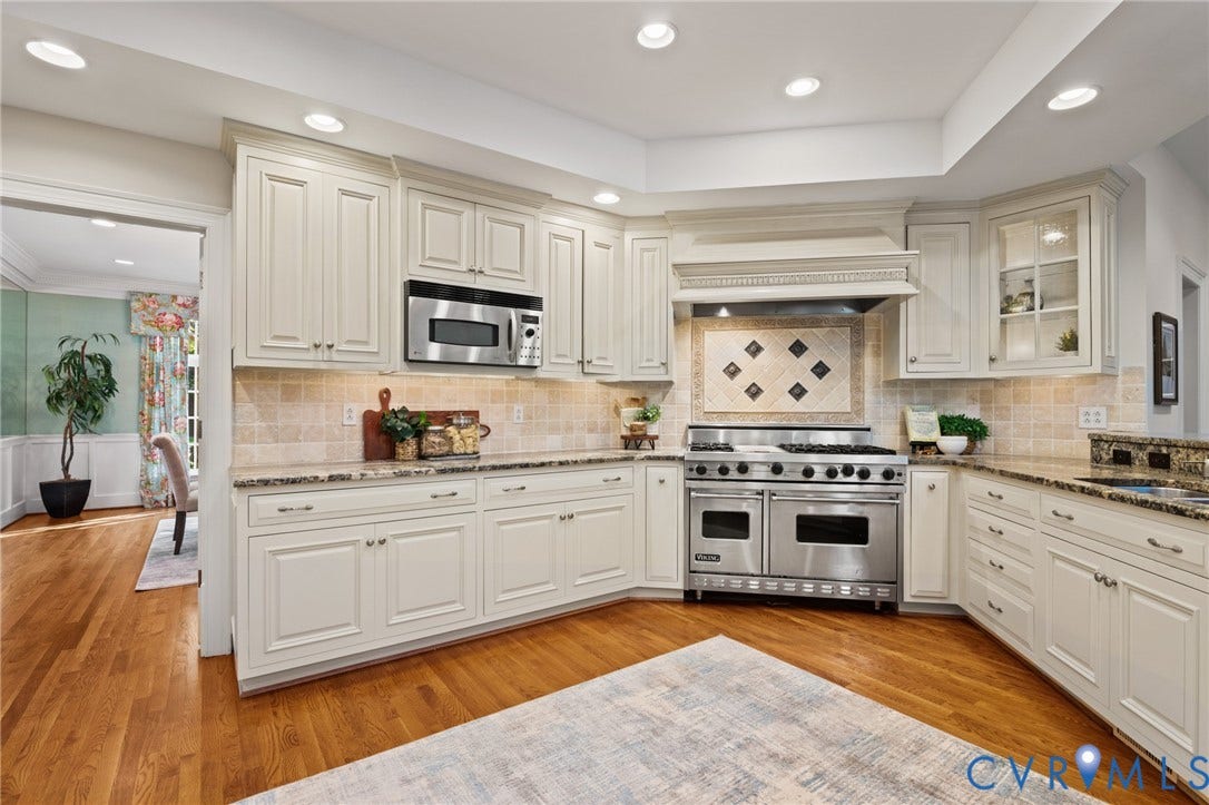 11429 Barrington Bridge Court, Henrico, VA 23233 Kitchen featuring off-white cabinetry, stone-finish countertops, tile backsplash with decorative inset, stainless steel double oven range, and wood-finish flooring