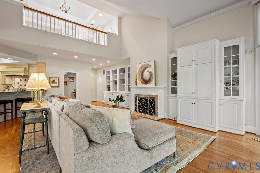 11429 Barrington Bridge Court, Henrico, VA 23233 Vaulted ceilings with mezzanine overlook, fireplace with carved mantle, extensive built-in cabinetry with glass display panels, recessed lighting, and wood-finish flooring