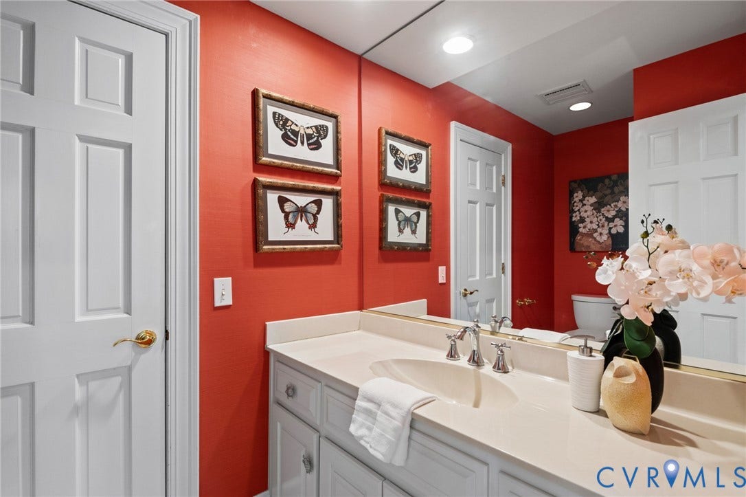 11429 Barrington Bridge Court, Henrico, VA 23233 Bathroom vanity featuring a solid surface countertop, an integrated oval sink, and a multi-paneled cabinet base with hardware, paired with a full-width wall mirror and polished metal faucet fixtures