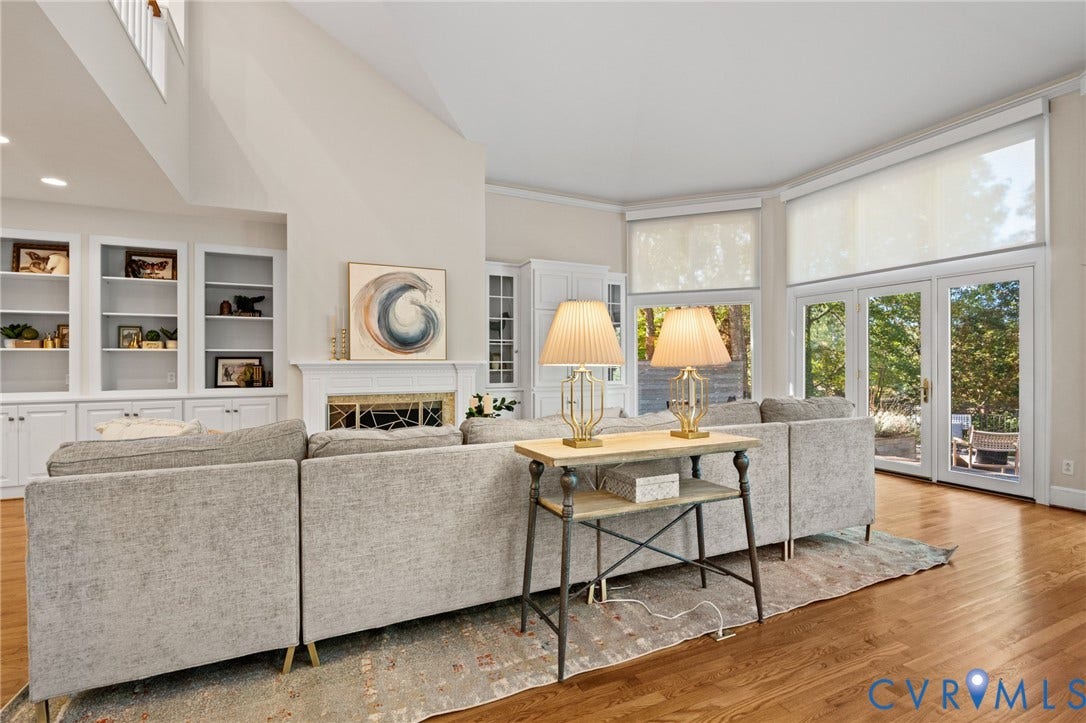 11429 Barrington Bridge Court, Henrico, VA 23233 Vaulted ceiling with expansive windows, wood-finish flooring, floor-to-ceiling built-in cabinetry, and a fireplace with a decorative metal screen