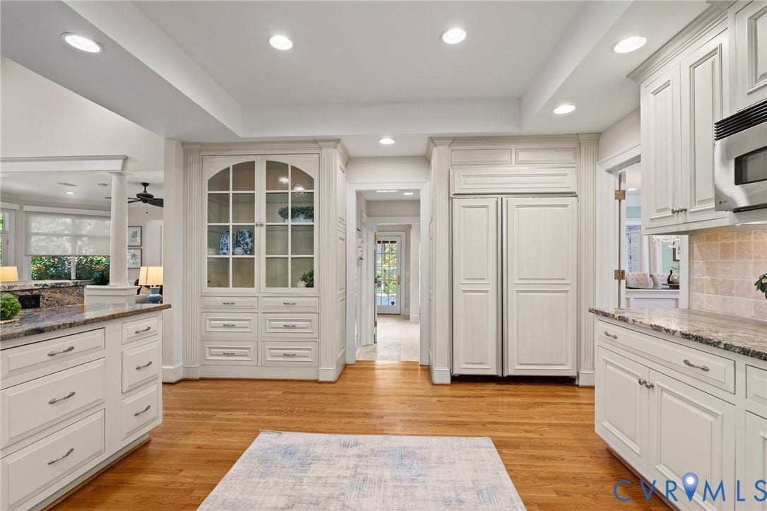 11429 Barrington Bridge Court, Henrico, VA 23233 Custom off-white cabinetry featuring glass-paneled display doors, integrated panel-front refrigerator, stone countertops, recessed ceiling lighting, and wood-finish flooring