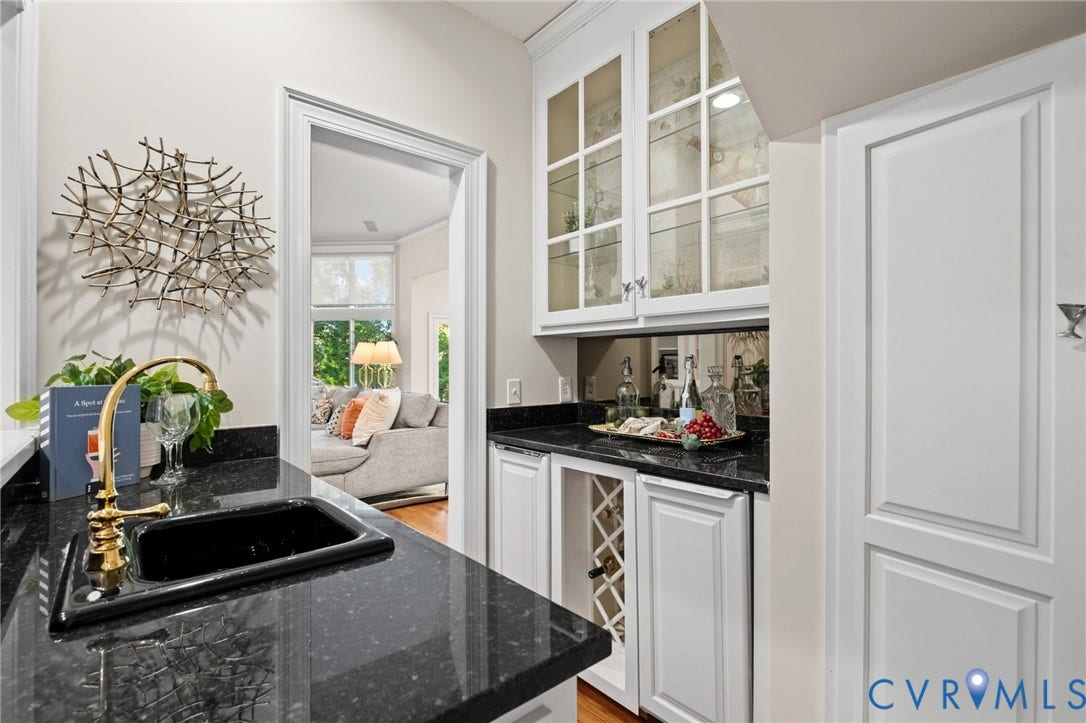 11429 Barrington Bridge Court, Henrico, VA 23233 Wet bar featuring dark stone countertops, custom white cabinetry, a built-in wine rack, glass-front upper cabinet doors, and a gold-toned faucet