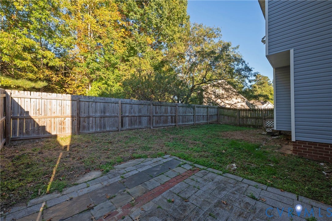 7009 Summers Trace Court, Chesterfield, VA 23832 Backyard featuring a stone paver patio, wood privacy fencing, and exterior vinyl siding with brick foundation detail