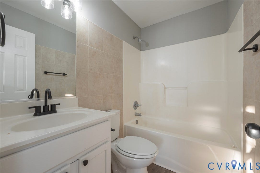 7009 Summers Trace Court, Chesterfield, VA 23832 Hall bathroom featuring a white vanity with a rectangular sink, matte black faucet, wall-mounted mirror with integrated lighting, and a neutral tile surround tub-shower combination