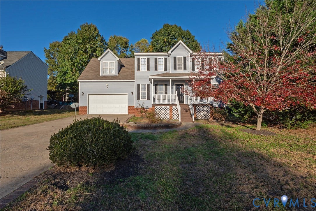 7009 Summers Trace Court, Chesterfield, VA 23832 Two-story home with light blue siding, decorative shutters, a covered front porch, integrated two-car garage, and a brick-accented foundation