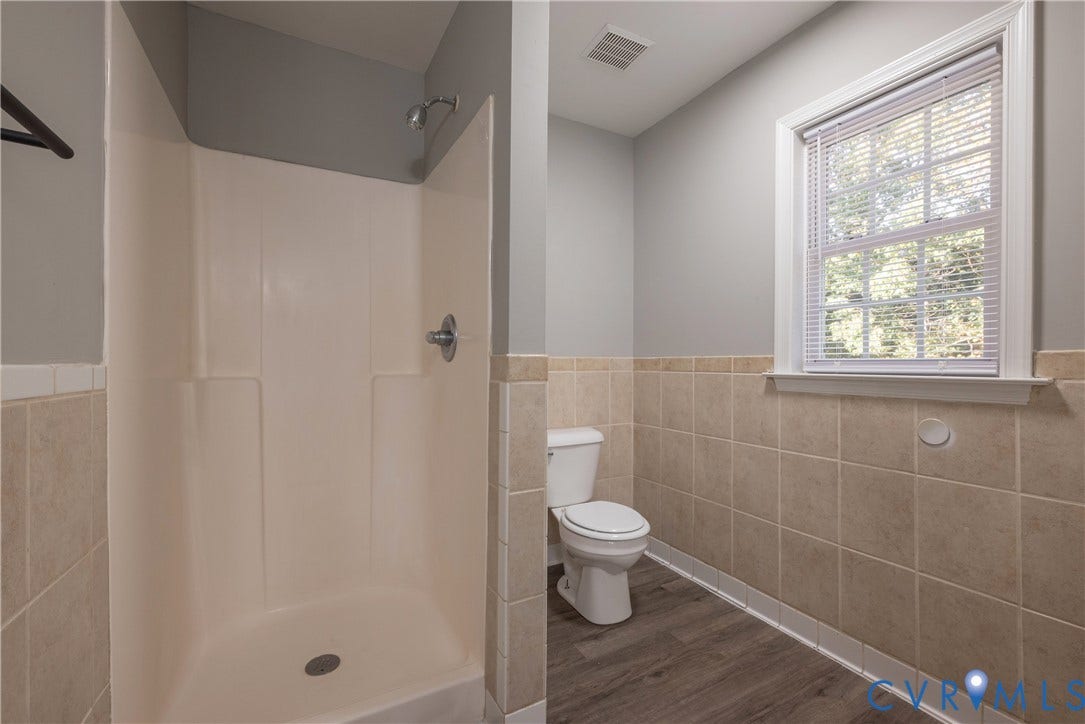 7009 Summers Trace Court, Chesterfield, VA 23832 Bathroom featuring a walk-in shower with integrated surround, dual-toned wall tile wainscoting, wood-finish flooring, and a window with blinds