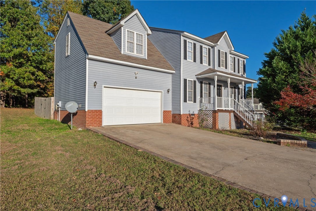 7009 Summers Trace Court, Chesterfield, VA 23832 Two-story residence featuring light-blue vinyl siding, a red brick foundation, an attached two-car garage, a covered front porch with railing, and multi-pane windows with shutters