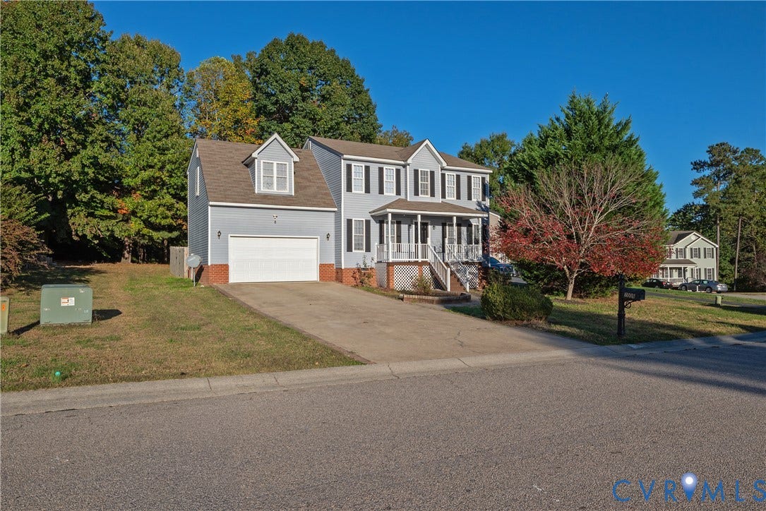 7009 Summers Trace Court, Chesterfield, VA 23832 Two-story residence featuring a front porch with a white railing, a double-car garage, brick veneer accents, and an expansive lawn