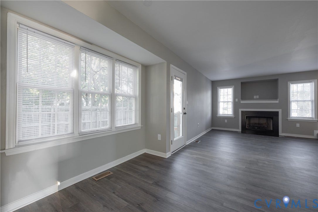 7009 Summers Trace Court, Chesterfield, VA 23832 Family Room area featuring new flooring, a fireplace with a black surround, recessed media niche, multiple windows, and a glass-paneled exterior door