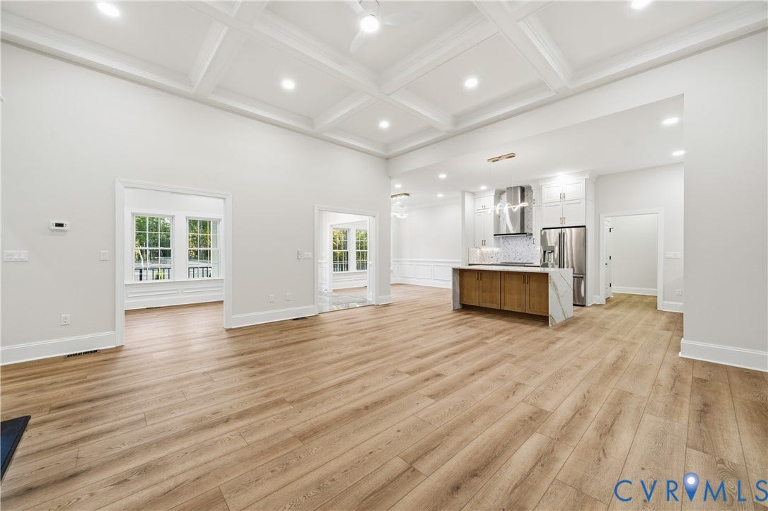 Coffered ceiling, wood-finish flooring, kitchen island with waterfall-edge countertop, recessed lighting, and stainless steel kitchen appliances