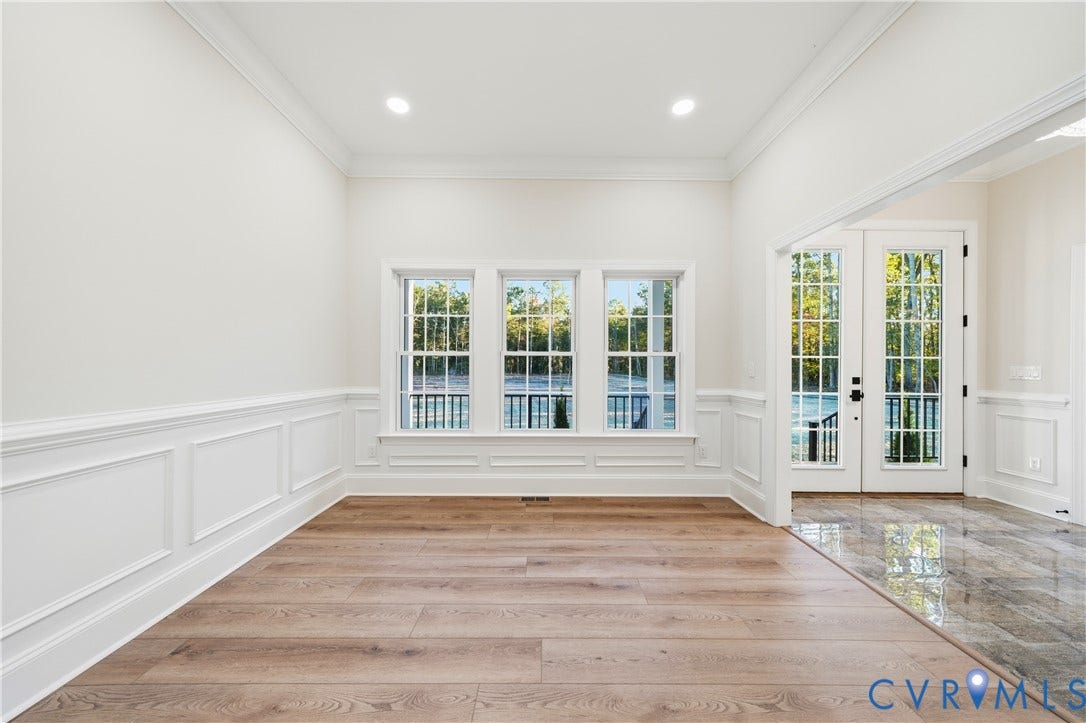 Room featuring wood-finish flooring, wainscoting, crown molding, recessed lighting, and a set of glass-paned double doors