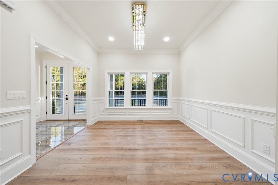Room featuring wood-finish flooring, wainscoting, triple windows, recessed lighting, and a crystal chandelier