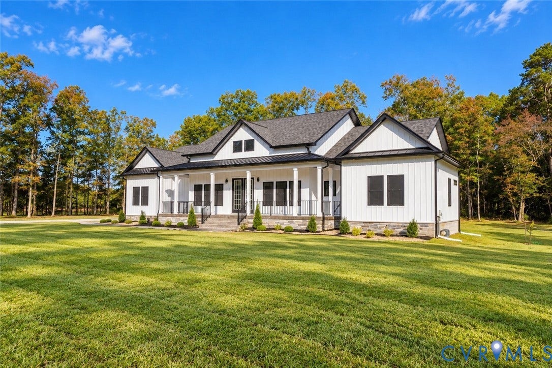 Modern farmhouse exterior featuring vertical white siding, stone veneer foundation, expansive covered front porch, and a shingle roof