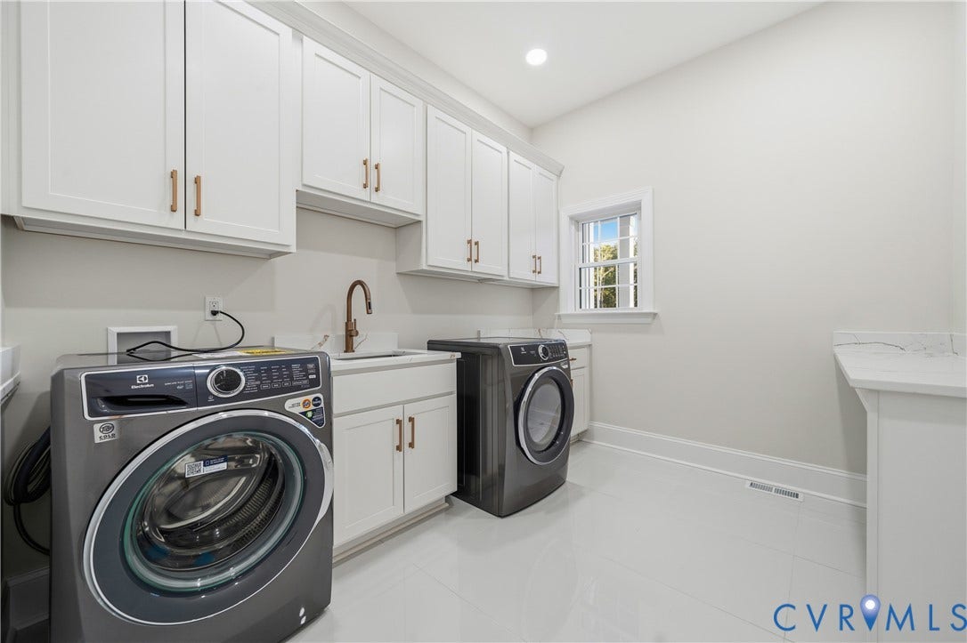 Laundry room featuring white Shaker-style cabinetry, matte bronze hardware, integrated sink, stone-finish countertops, and tile flooring