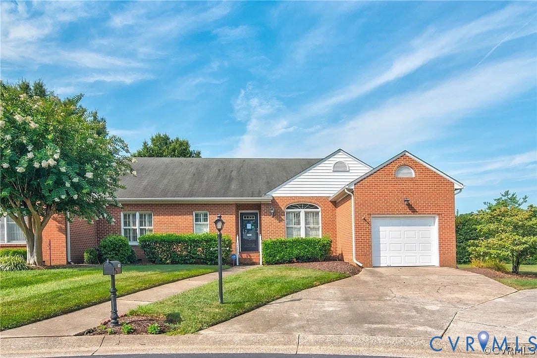 Brick exterior residence featuring a front-facing attached garage, arched window accents, white siding gables, and a concrete driveway