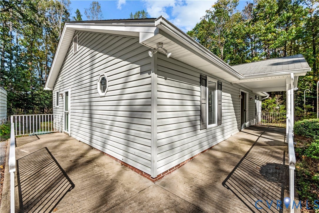 20040 Paradise Lane, Ruther Glen, VA 22546 Exterior featuring light gray horizontal siding, a wrap-around concrete porch, white metal railings, and a decorative octagonal window