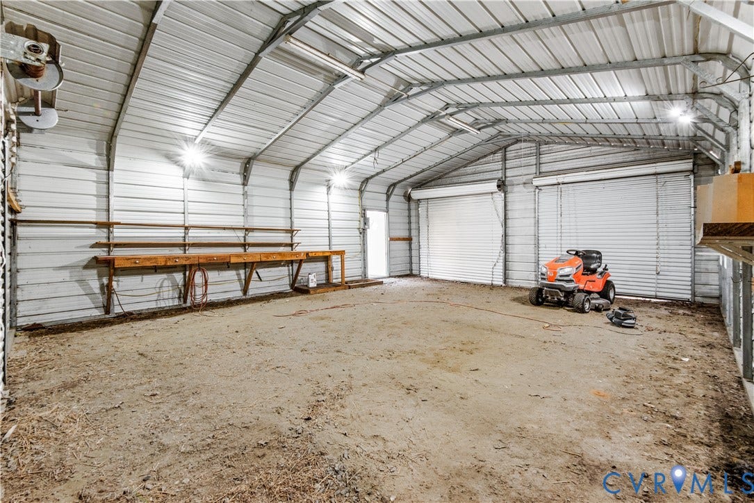 20040 Paradise Lane, Ruther Glen, VA 22546 Spacious metal-sided detached garage featuring two roll-up doors, high vaulted ceilings, and a built-in wooden workbench