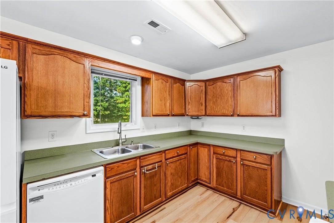 20040 Paradise Lane, Ruther Glen, VA 22546 Kitchen featuring wood cabinetry, solid-surface countertops, dual-basin stainless steel sink, wood-finish flooring, and built-in dishwasher