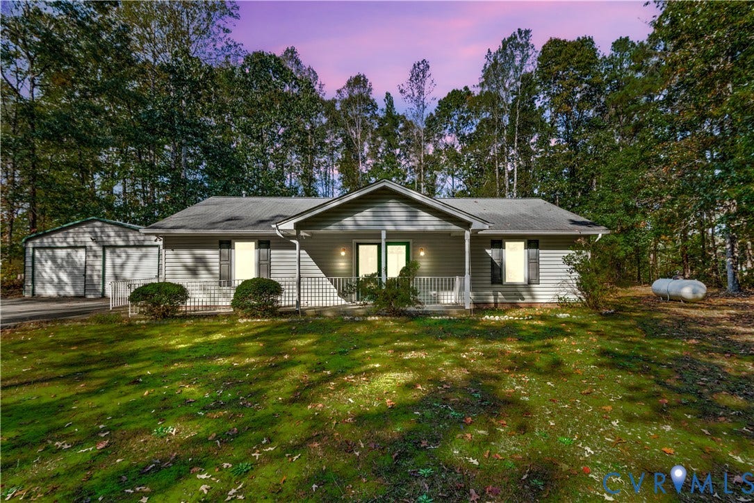 20040 Paradise Lane, Ruther Glen, VA 22546 Single-story residence featuring horizontal lap siding, an expansive covered front porch with white railing, and a detached two-car garage