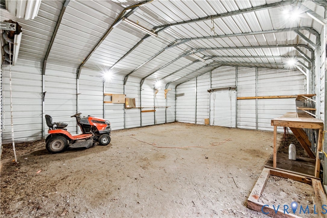 20040 Paradise Lane, Ruther Glen, VA 22546 Enclosed metal workshop featuring corrugated wall and ceiling panels, integrated ceiling-mounted lighting, and built-in timber shelving